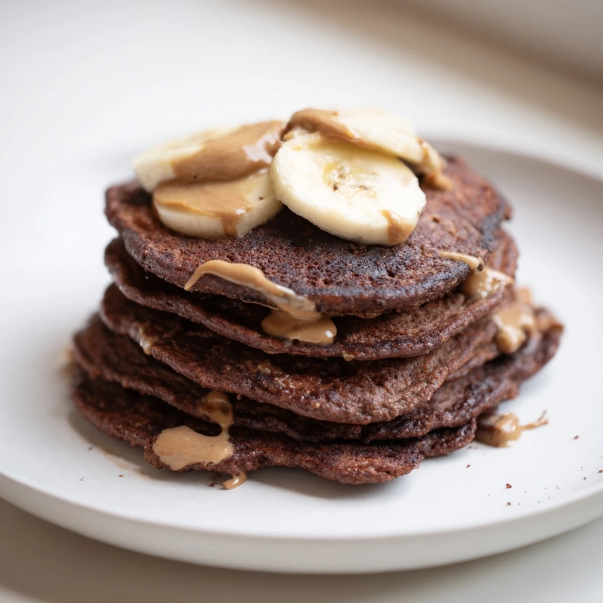 Delicious Banana Chocolate Pancakes served with fresh fruit and nut butter drizzles.  
