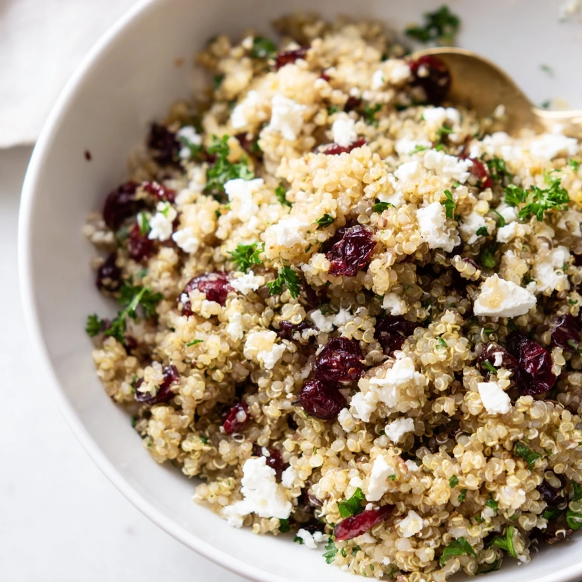 A colorful quinoa salad with feta, cranberries, and fresh parsley drizzled with vinaigrette.  