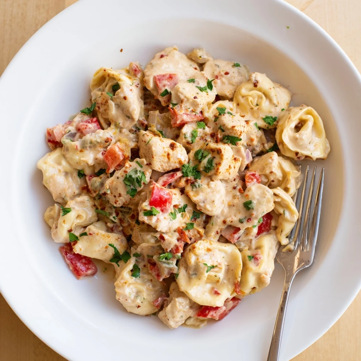 Zesty Cajun Garlic Parmesan Chicken Tortellini in creamy sauce, garnished with fresh parsley.  