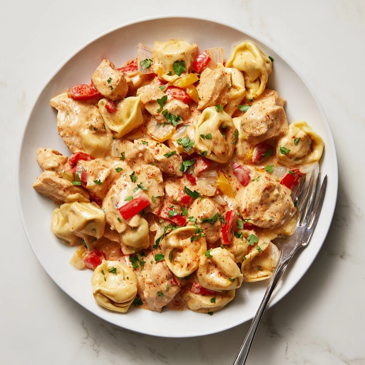 Flavorful Zesty Cajun Garlic Parmesan Chicken Tortellini served with parsley and extra cheese.  