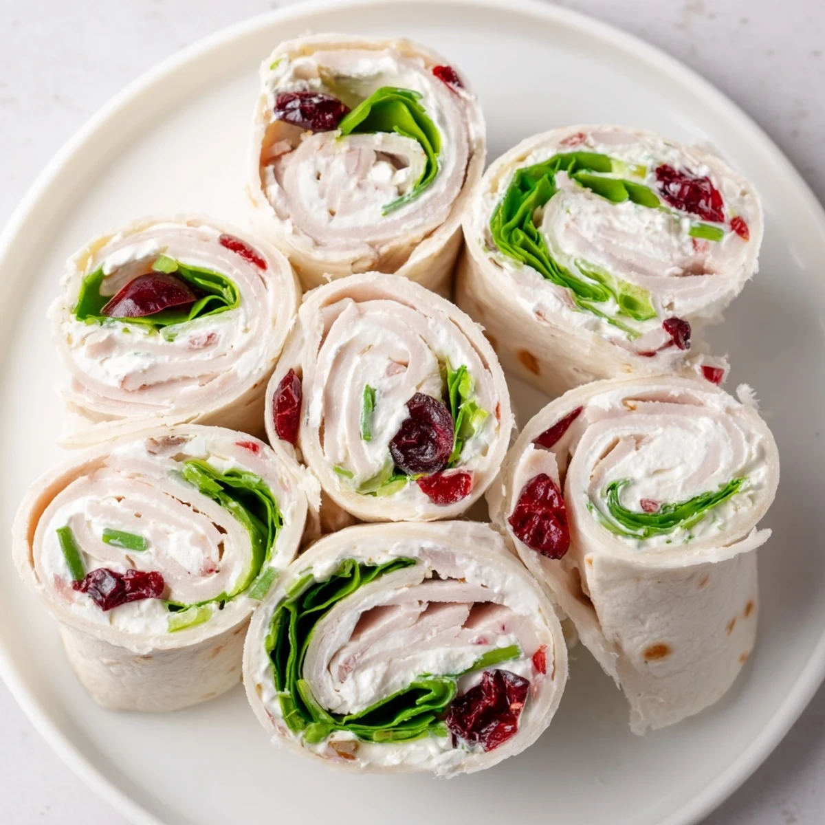 Platter of colorful Simplified Turkey Cranberry Pinwheels, ready to serve, a delicious and easy holiday appetizer.