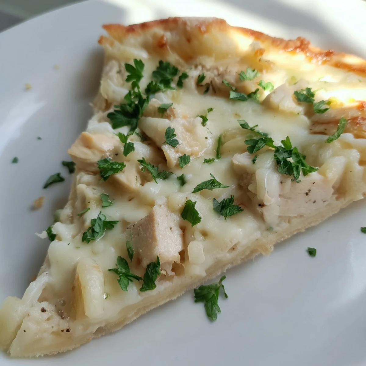 Homemade Chicken Alfredo Pizza with golden edges, rich Alfredo sauce, chicken, and melted cheeses on a rustic pan.
