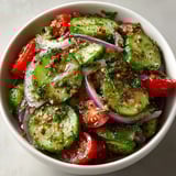 Close-up of Marinated Cucumbers, Onions, and Tomatoes featuring vibrant colors and crisp vegetable textures.