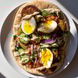 A warm pita overflowing with vibrant Israeli Sabich: fried eggplant, eggs, and fresh flavors.