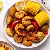 A flavorful Cajun shrimp and sweet corn platter garnished with fresh parsley.  