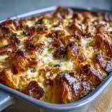 Warm, custardy Ham and Cheese Croissant Bake Casserole with layers of buttery croissants, smoky ham, and rich cheese, topped with fresh chives.  