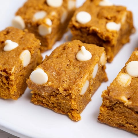 Moist pumpkin muffin white chocolate chip bars drizzled with melted chocolate, perfect for fall.  