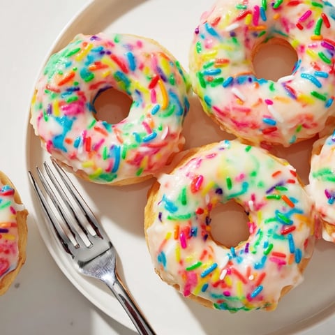 Fluffy cream soda birthday cake donuts topped with colorful glaze and sprinkles.  