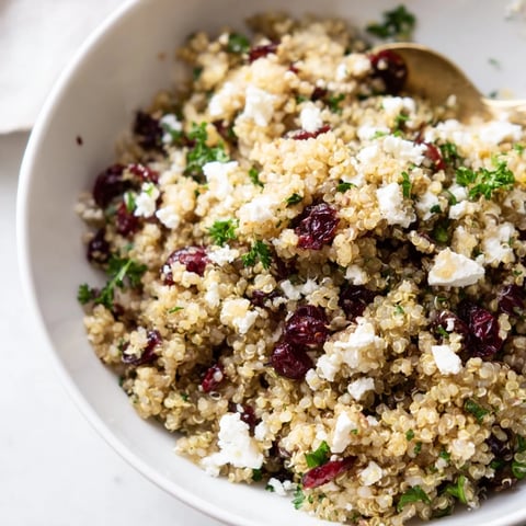 A colorful quinoa salad with feta, cranberries, and fresh parsley drizzled with vinaigrette.  