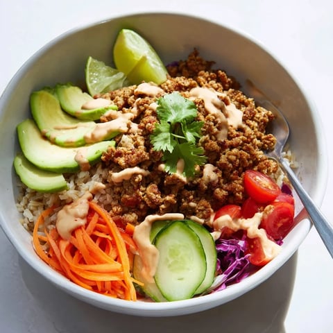 A colorful Plant-Based Meat Bowl topped with fresh veggies and zesty lime wedges.  