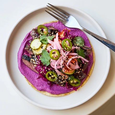 Delicious Global Street-Food Fusion Tacos topped with vibrant ube crema and fresh cilantro.