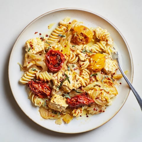 Creamy baked feta pasta with caramelized onions, bursting cherry tomatoes, and herbs.
