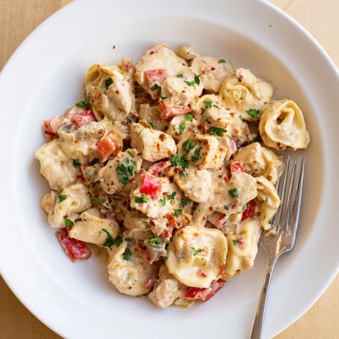 Zesty Cajun Garlic Parmesan Chicken Tortellini in creamy sauce, garnished with fresh parsley.  