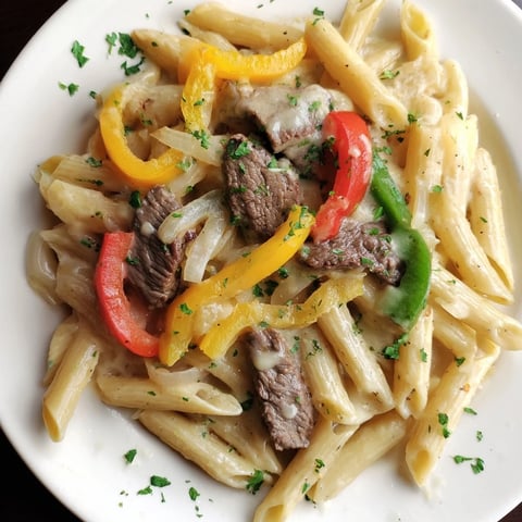 Steaming bowl of Philly cheesesteak pasta, a comforting blend of beef, peppers, and creamy cheese.