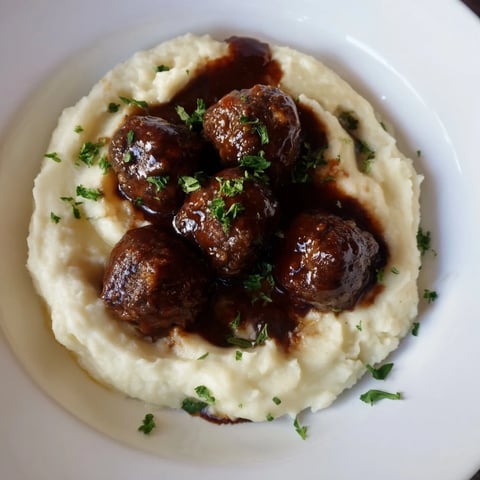Golden-brown BBQ meatballs smothered in tangy sauce, paired with fluffy mashed potatoes, a classic comfort meal.