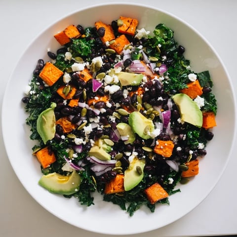 Vibrant massaged kale salad with sweet potato, black beans, and lime dressing, ready to eat!
