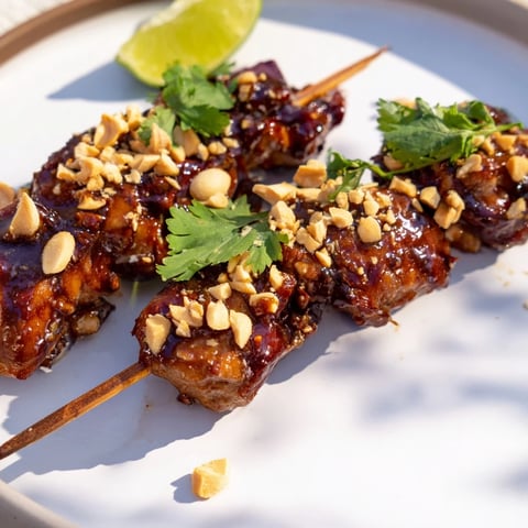 Juicy Spicy Peanut Satay Chicken Skewers, charred from the grill and ready to serve with fresh cilantro.