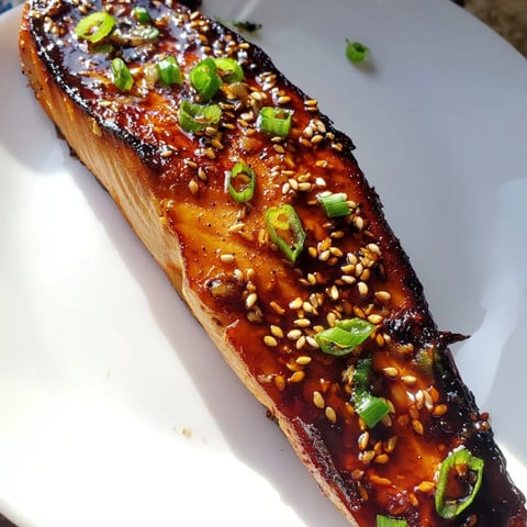 Pan-seared ginger soy glazed salmon, glistening with a rich glaze, served with fresh green onions.