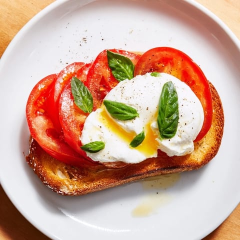 Golden, toasted sourdough holds fresh Tomato Burrata Toast, bursting with vibrant red tomatoes and creamy cheese.