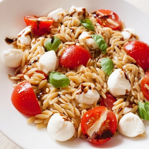 Vibrant Caprese Orzo Salad featuring juicy tomatoes, creamy mozzarella, and a light balsamic dressing.