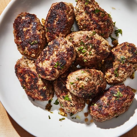 Golden-brown Turkish Köfte meatballs, pan-fried to perfection, are ready to serve with fresh herbs.