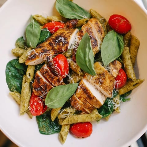 Grilled pesto chicken pasta with vibrant tomatoes, perfect for a flavorful Italian dinner.