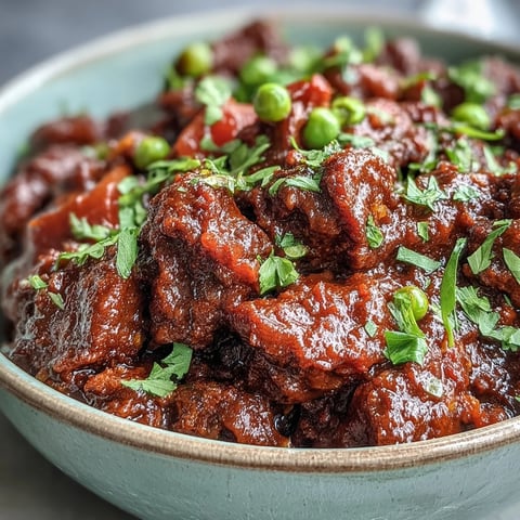 Freshly cooked Venison Keema Curry with tender ground meat, green peas, and aromatic Indian spices steaming in a rustic skillet.
