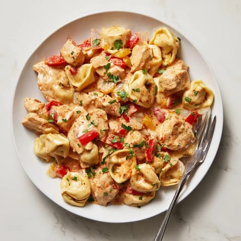 Flavorful Zesty Cajun Garlic Parmesan Chicken Tortellini served with parsley and extra cheese.  