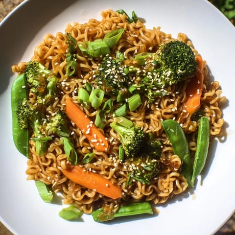 Steaming bowl of Ramen Noodle Stir-Fry Remix, with colorful veggies and a savory sauce aroma.