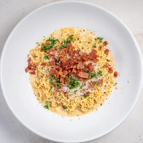 Quick, flavorful carbonara ramen, overflowing with perfectly coated noodles and fresh parsley garnish.
