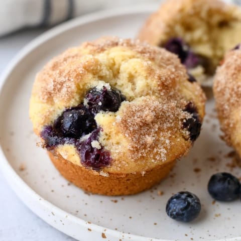 Fluffy Budget Christmas Blueberry Muffins, golden brown, with a sprinkle of cinnamon-sugar topping, ready to eat.