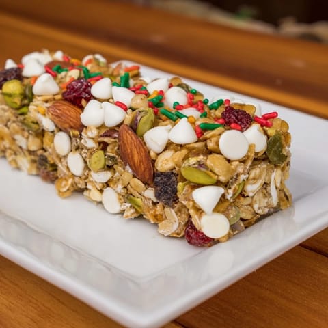 Golden-brown Winter Wonderland Trail Mix Bar cut in squares, showcasing the textures of nuts and oats.