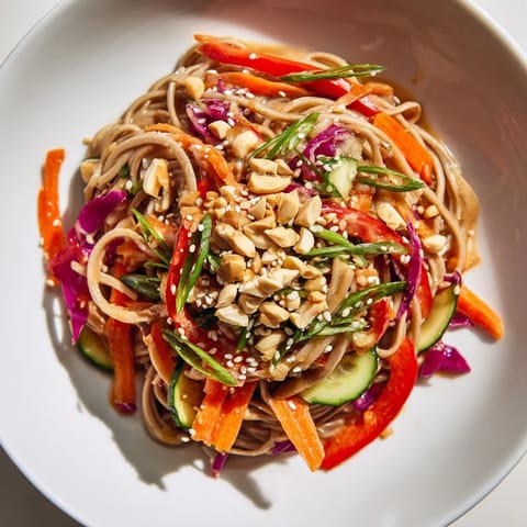 Beautiful bowl of Cold Noodle Salad with sesame-ginger dressing, garnished with peanuts and seeds.