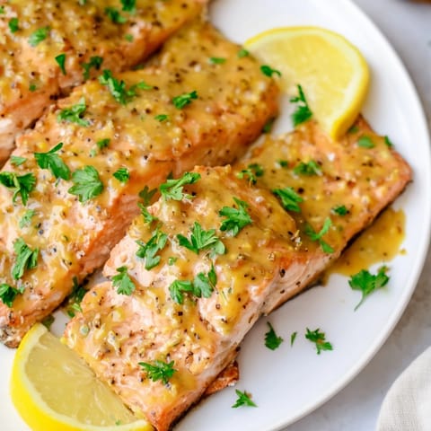 Honey mustard salmon fillets ready to eat, showing flaky texture and vibrant green parsley garnish.