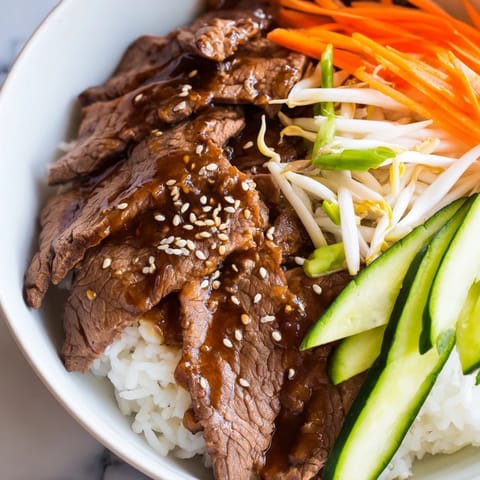 Savory bulgogi beef bowl with glistening, marinated beef strips, served on a bed of fluffy white rice.