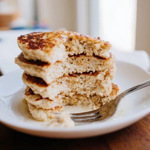 Golden-brown Protein Power Pancakes sizzling on a griddle, surrounded by a bowl of Greek yogurt and mixed berries.