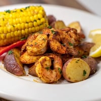 Spicy Cajun shrimp and sweet corn platter served on a colorful table setting.  