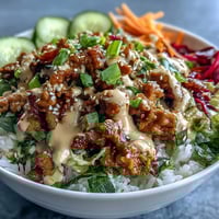 Fragrant ground turkey and crisp veggies for Spicy Bang Bang Turkey Rice Bowls, topped with creamy sauce and sesame seeds.