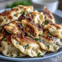 Golden pan-fried vegetable pierogi with sour cream and parsley garnish.